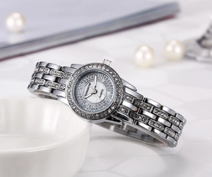 Close-up of elegant silver ladies' watch with rhinestone bezel and shell dial texture.