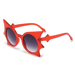 Lunettes de soleil rouges forme chauve-souris avec verres dégradés gris sur fond blanc