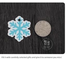 Blue and white snowflake gift tags shown next to a coin for size scale on wood background