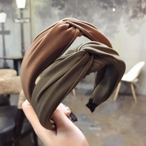 Close-up of camel and olive green knotted fabric headbands held in a cafe setting