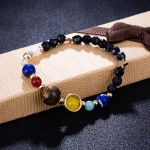 Sonnensystem-Armband mit Natursteinen und Goldsternen auf einer Geschenkbox