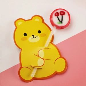 Macro shot of a yellow bear lollipop paper card holder with a cherry pattern candy