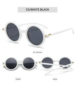 Detail view of round white acetate sunglasses with gold metal sphere accents and dark lenses