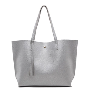 Close-up of silver tote bag with lychee texture, metallic magnetic buckle and tassel detail