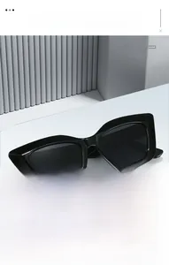 Gros plan de lunettes de soleil œil de chat noires sur un présentoir géométrique blanc