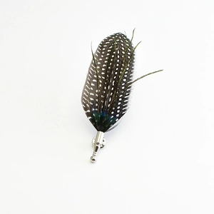 Detailed view of handmade feather brooch with black and white spots and green peacock sheen