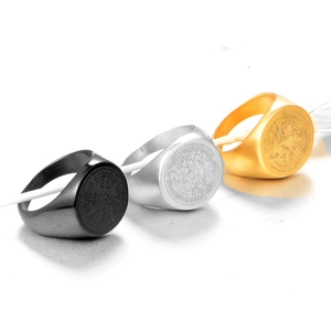 Detailed macro view of men's stainless steel compass signet rings in black, gold, and silver