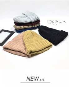 Stack of colorful ribbed knit beanies in gray, burgundy, navy, and pink on white background