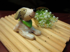 Close-up of a miniature resin dog figurine with a green scarf on a bamboo mat