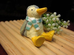 Macro shot of a mini hand-painted resin penguin figurine with blue striped scarf