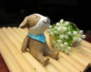 Detail of vintage resin puppy ornament with blue polka dot scarf on bamboo mat