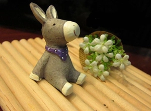 Detailed view of miniature grey donkey resin figurine with purple polka dot scarf on mat