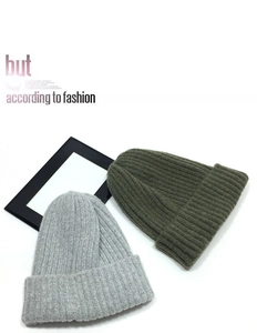 Detailed knit texture of light grey and olive green winter beanies with folded cuffs