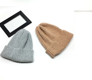 Detailed close-up showing the vertical ribbed knit texture of light grey and camel beanies