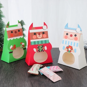 Three Christmas cartoon gift boxes with windows in red, green, and white on a wood table