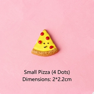 Detail of pizza-shaped resin DIY accessory with cartoon face and red dots on pink surface