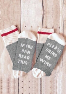 Detail of grey sock soles with white funny wine slogan lettering on wood background