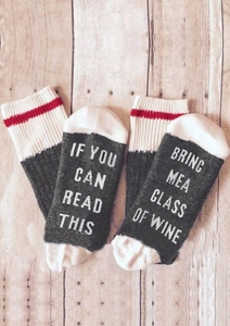 Detailed view of novelty cotton socks with funny text and red striped cuffs on wood