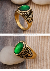 Macro view of men's vintage gold ring featuring a large green gemstone and carved details