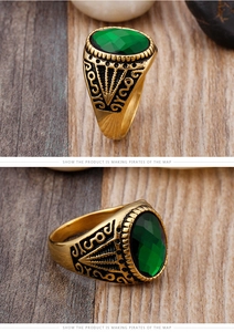 Close-up of vintage gold ring featuring a large green faceted gem and ornate black carving