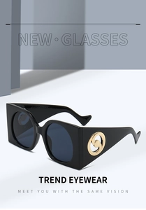 Close-up of black oversized sunglasses featuring a unique gold metal hinge ornament