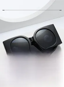 Detail of oversized retro sunglasses with black frames on a white geometric display