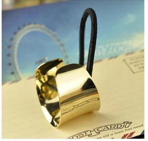 Close-up of minimalist gold polished metal ponytail holder cuff with black elastic band