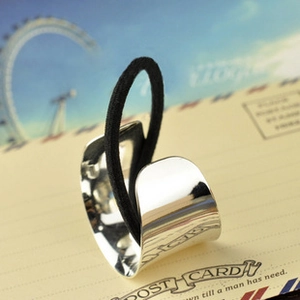 Polished silver metal hair cuff with black elastic band on vintage postcard background