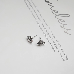 Detailed view of silver bee stud earrings with textured wings and vintage finish