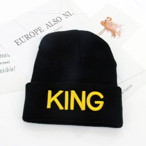 Black knitted beanie hat with yellow KING embroidery shown on minimalist background
