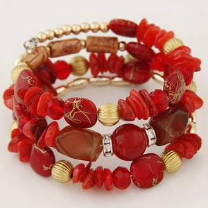 Macro shot of ethnic multi-layer bracelet with red stones, gold beads and wood accents