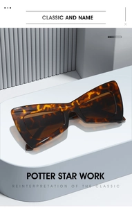 Detail of tortoiseshell cat-eye sunglasses with brown lenses on a minimalist pedestal