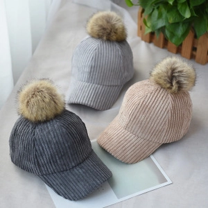 Macro shot of corduroy texture and plush pom poms on winter baseball caps in gray and beige