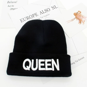 Black knitted beanie hat with white bold QUEEN letter embroidery on a white background