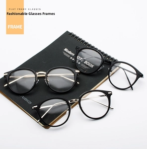 Detailed view of black full-frame eyeglasses with gold metal temples on a notebook