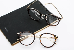 Detail view of round retro frames in black and tortoiseshell with gold metal temples