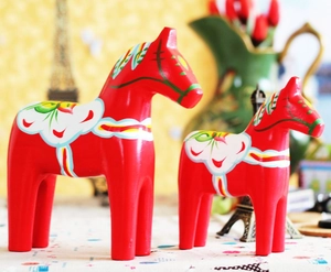 Detail of red wooden Dala Horse statues with traditional hand-painted Kurbits floral patterns