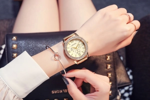 Close-up of luxury gold ladies watch with crystal bezel and three-eye dial on wrist