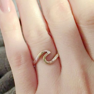 Close-up of a unique wave-shaped titanium steel ring shown on a finger
