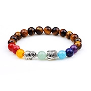 Macro detail of tiger eye beads with silver Buddha and elephant charms on chakra bracelet