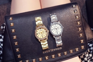 Detail of luxury rhinestone bezel quartz watches with metal strap on black leather clutch