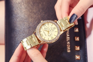 Macro detail of gold dial with rhinestones and decorative sub-dials on a metal watch