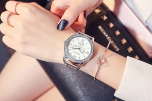 Detail of silver ladies watch with rhinestone bezel paired with elegant jewelry
