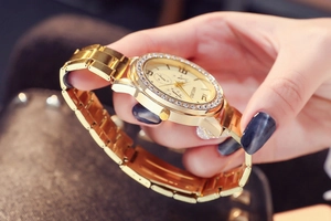 Close-up of women's gold watch with rhinestone bezel and three-eye decorative dial