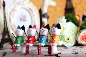 Macro detail of four colorful wooden fishing cat figurines on a white wooden bench decor