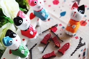 Detail of colorful wooden fishing cat figurines with mini rods and red fish accessories