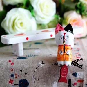 Macro view of hand-painted wooden cat figurine with fishing rod and a small red fish