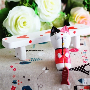 Detail of hand-painted wooden fishing cat figurine with red kimono on a white bench