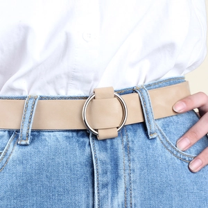 Women's beige leather belt with round silver buckle on jeans, minimalist fashion style