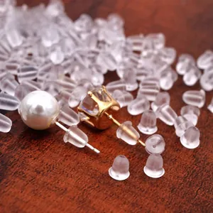 Dettaglio di chiusure per orecchini in silicone con perni di perle su base di legno